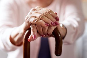 Pflege zu Hause – ältere Frau hält einen Gehstock