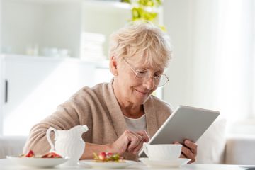 Senior Dame schaut auf Tablet