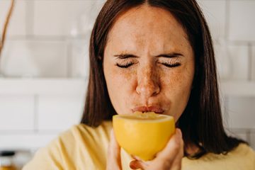 Frau beißt in eine Zitrone, um ihr Immunsystem zu stärken