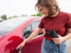 E-Mobilität: Frau in roten T-shirt hält Stecker für Elektroauto