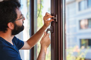 Mann rüstet Fenster mit Sicherheitstechnik nach