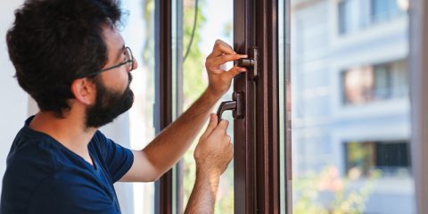 Mann rüstet Fenster mit Sicherheitstechnik nach