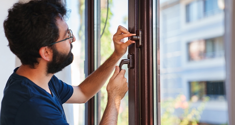 Mann rüstet Fenster mit Sicherheitstechnik nach