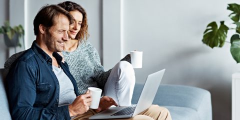 Ehepaar sitzt interessiert vor Laptop und hört sich einen Vortrag an